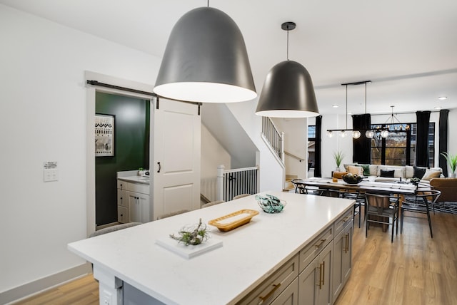 kitchen featuring pendant lighting, a barn door, a center island, and light hardwood / wood-style flooring