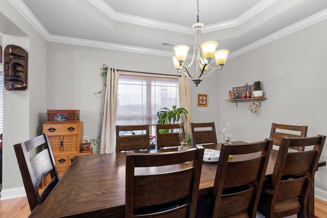 dining space with hardwood / wood-style flooring, an inviting chandelier, and a tray ceiling