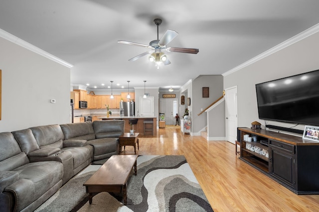 living room with crown molding, ceiling fan, and light wood-type flooring