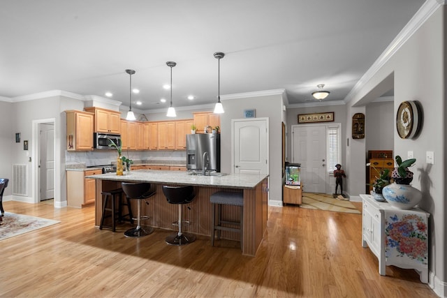 kitchen featuring light stone countertops, a center island with sink, light brown cabinets, and appliances with stainless steel finishes