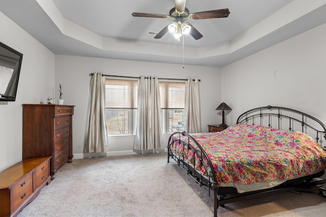 carpeted bedroom with ceiling fan and a tray ceiling