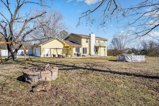 rear view of property featuring a fire pit and a balcony