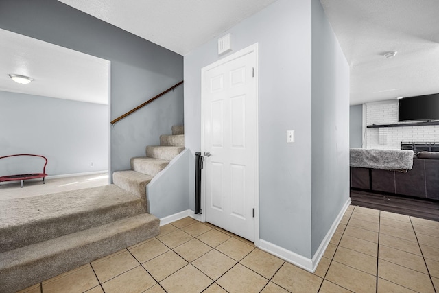 stairway with a brick fireplace and tile patterned floors