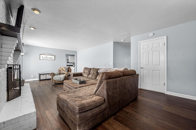 living room with dark wood-type flooring, a fireplace, and a textured ceiling