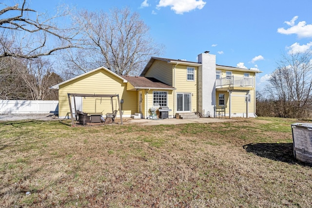 rear view of property with a balcony, a yard, and a patio area