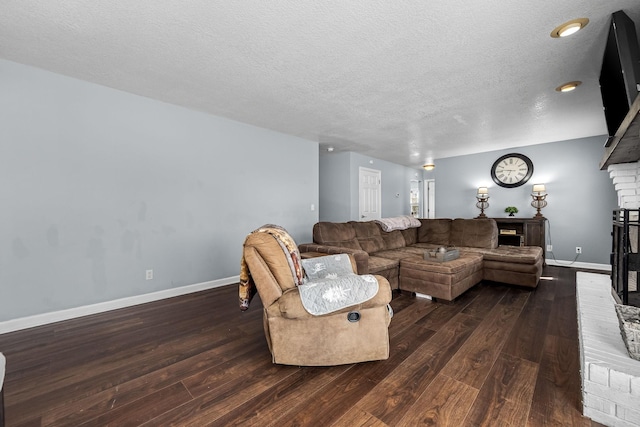 living room with a brick fireplace, dark hardwood / wood-style floors, and a textured ceiling