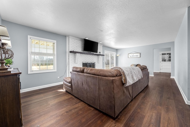 living room featuring a fireplace, dark hardwood / wood-style flooring, and a textured ceiling