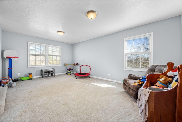 recreation room with carpet and a textured ceiling