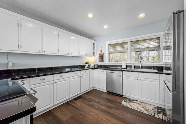 kitchen featuring sink, white cabinets, dark hardwood / wood-style flooring, stainless steel appliances, and a textured ceiling