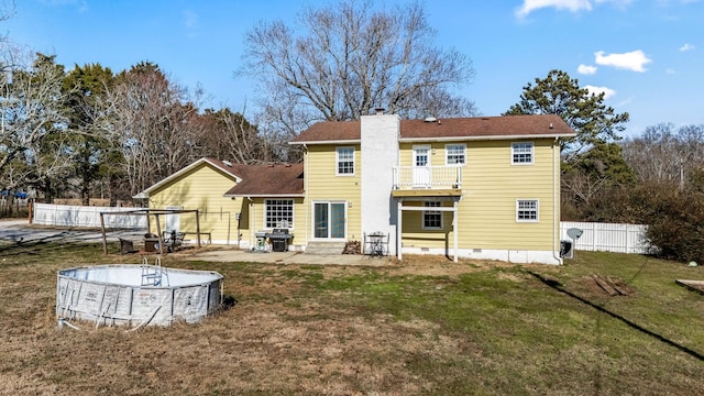 rear view of house featuring a fenced in pool, a lawn, a patio, and a balcony