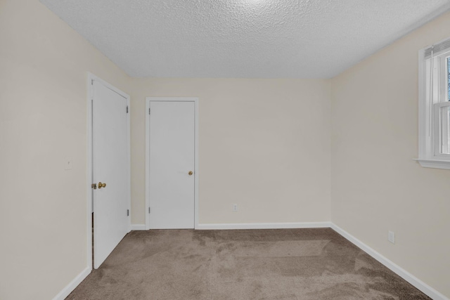 unfurnished room featuring light carpet and a textured ceiling