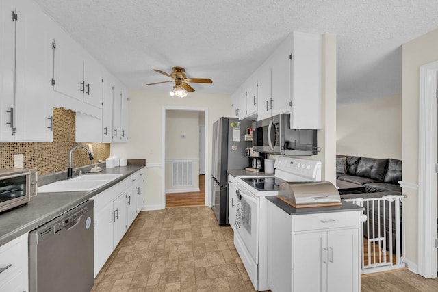 kitchen with sink, white cabinets, ceiling fan, stainless steel appliances, and backsplash