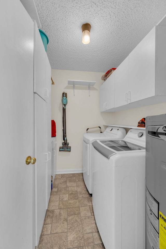 washroom with cabinets, electric water heater, a textured ceiling, and independent washer and dryer