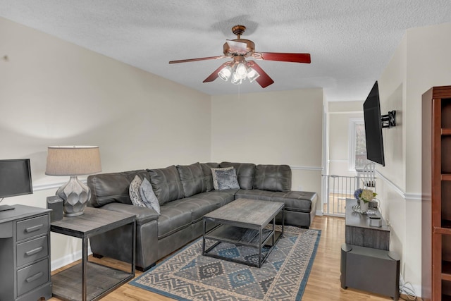 living room with ceiling fan, light hardwood / wood-style flooring, and a textured ceiling