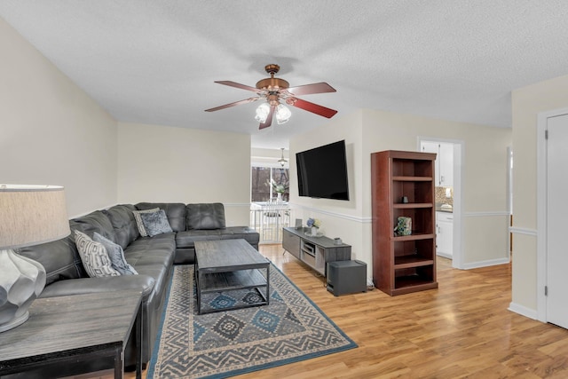 living room featuring ceiling fan, a textured ceiling, and light wood-type flooring