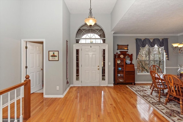 entryway with crown molding, a textured ceiling, and light wood-type flooring