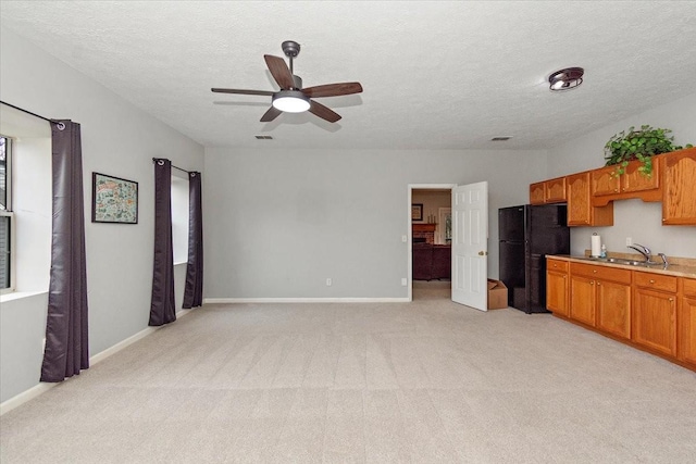 kitchen featuring sink, light colored carpet, ceiling fan, black fridge, and a textured ceiling