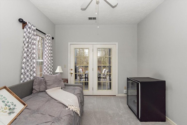 carpeted bedroom featuring ceiling fan, a textured ceiling, and french doors