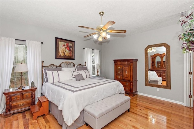 bedroom featuring ceiling fan, a textured ceiling, and light hardwood / wood-style flooring