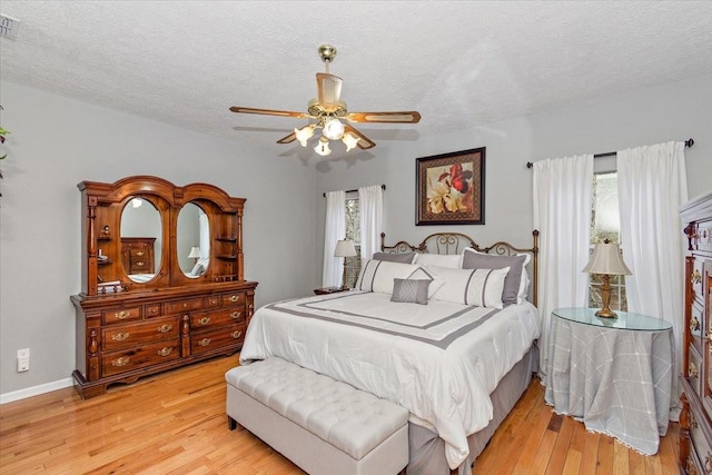 bedroom featuring ceiling fan, light hardwood / wood-style floors, and a textured ceiling