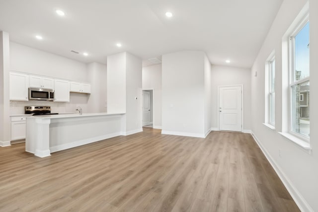 unfurnished living room featuring lofted ceiling, sink, and light hardwood / wood-style floors