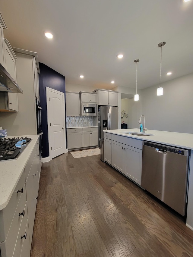 kitchen with a kitchen island, pendant lighting, sink, dark hardwood / wood-style flooring, and stainless steel appliances