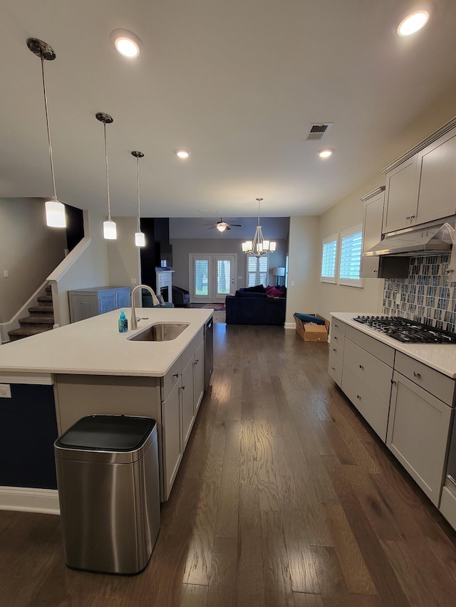 kitchen featuring sink, dark hardwood / wood-style flooring, hanging light fixtures, a kitchen island with sink, and gas stovetop