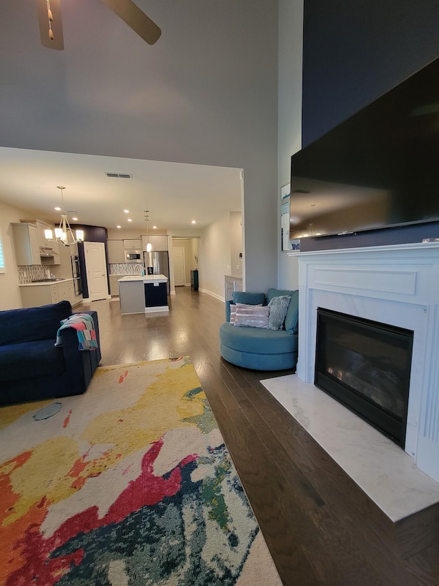 living room featuring hardwood / wood-style flooring, a high ceiling, and ceiling fan with notable chandelier