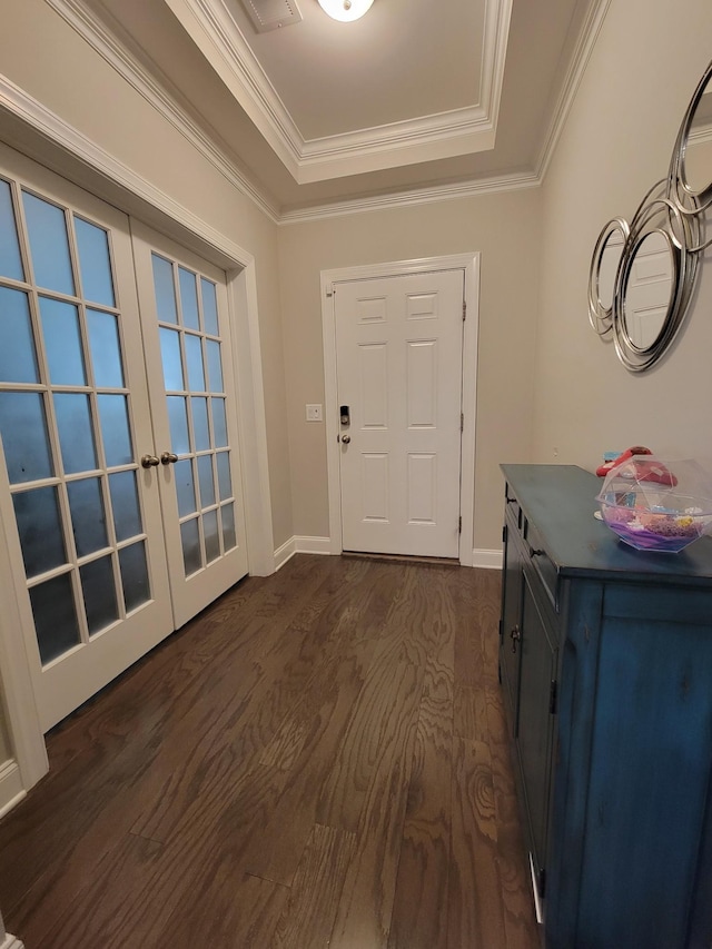 foyer entrance featuring ornamental molding, a tray ceiling, dark wood-type flooring, and french doors