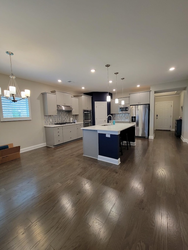 kitchen featuring pendant lighting, sink, decorative backsplash, a kitchen island with sink, and stainless steel appliances