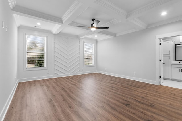 spare room featuring beam ceiling, coffered ceiling, a wealth of natural light, and light wood-type flooring