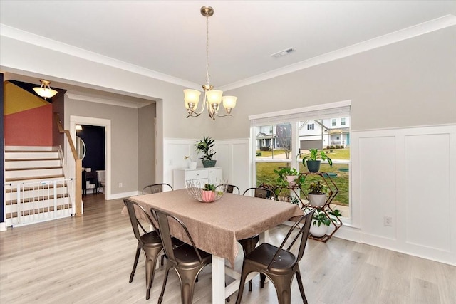 dining area with ornamental molding, light hardwood / wood-style flooring, and a notable chandelier