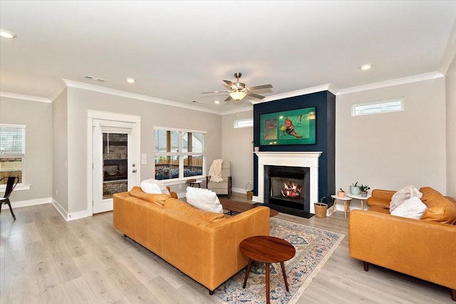 living room with light hardwood / wood-style flooring, crown molding, a fireplace, and a healthy amount of sunlight