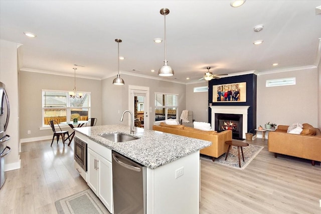 kitchen featuring appliances with stainless steel finishes, sink, white cabinets, light stone countertops, and a center island with sink