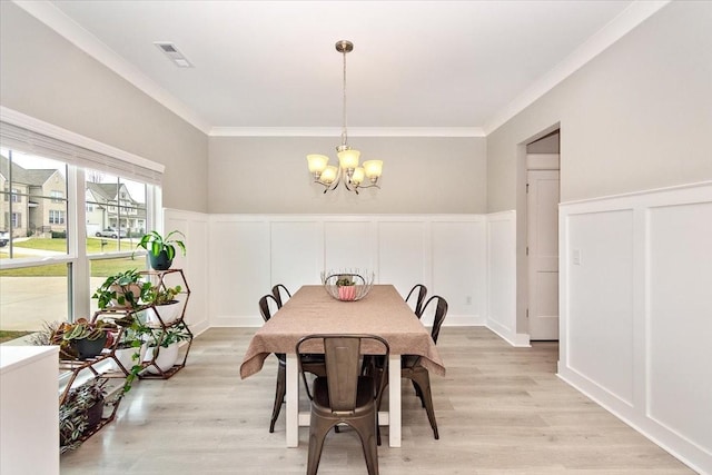 dining room with an inviting chandelier, ornamental molding, and light hardwood / wood-style flooring