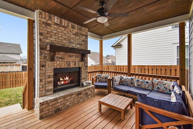 deck with ceiling fan and an outdoor living space with a fireplace