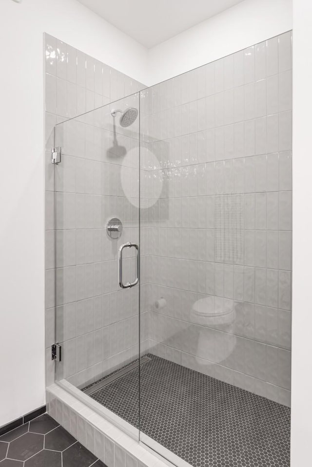 bathroom featuring tile patterned floors, toilet, and a shower with shower door