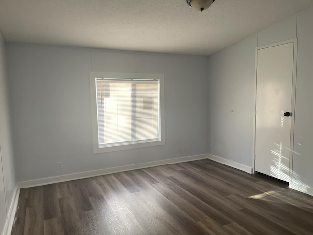 empty room featuring dark wood-type flooring and a textured ceiling