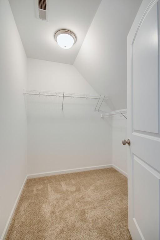 walk in closet with lofted ceiling and carpet