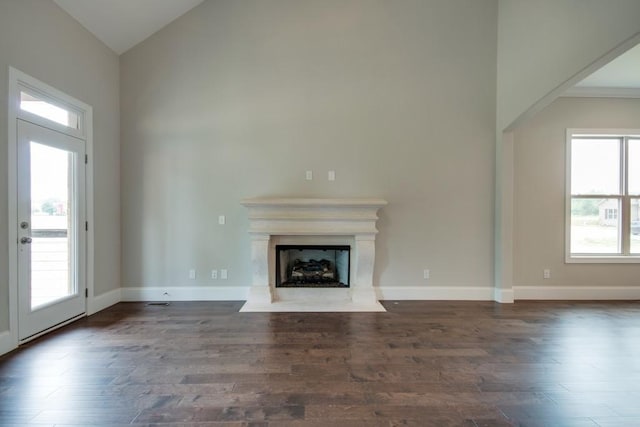 unfurnished living room featuring dark wood-type flooring and high vaulted ceiling