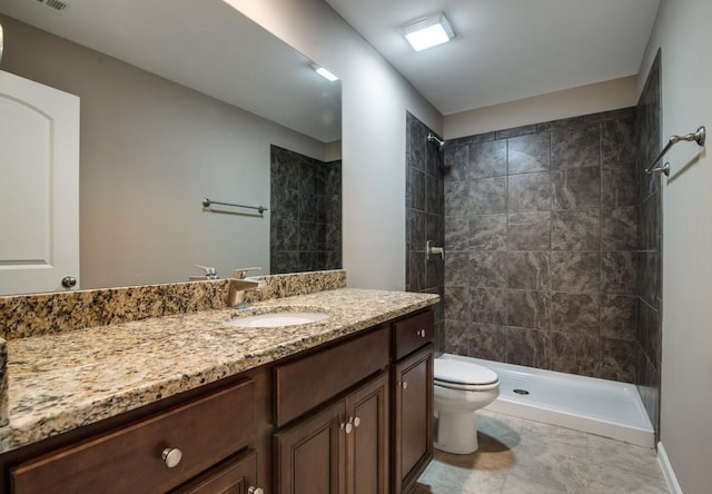 bathroom featuring vanity, toilet, and a tile shower