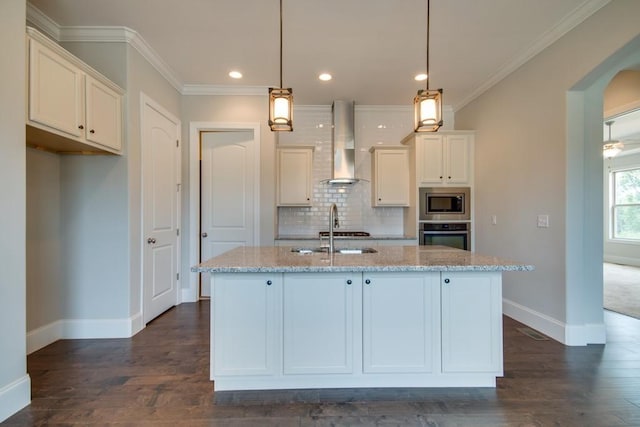 kitchen with light stone counters, white cabinetry, ventilation hood, a center island with sink, and stainless steel appliances