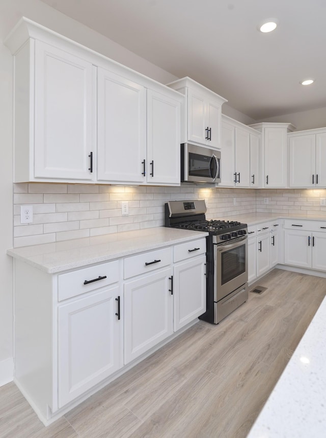 kitchen featuring white cabinetry, appliances with stainless steel finishes, and tasteful backsplash