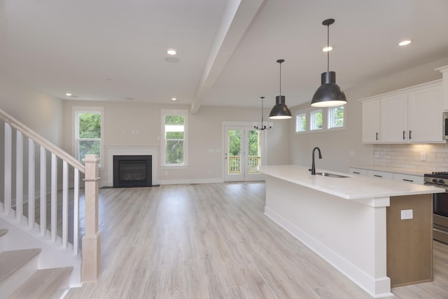 kitchen with sink, tasteful backsplash, appliances with stainless steel finishes, pendant lighting, and white cabinets