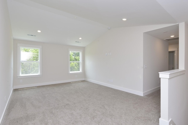 spare room featuring light carpet and lofted ceiling