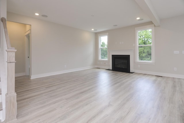 unfurnished living room featuring beam ceiling and light hardwood / wood-style flooring