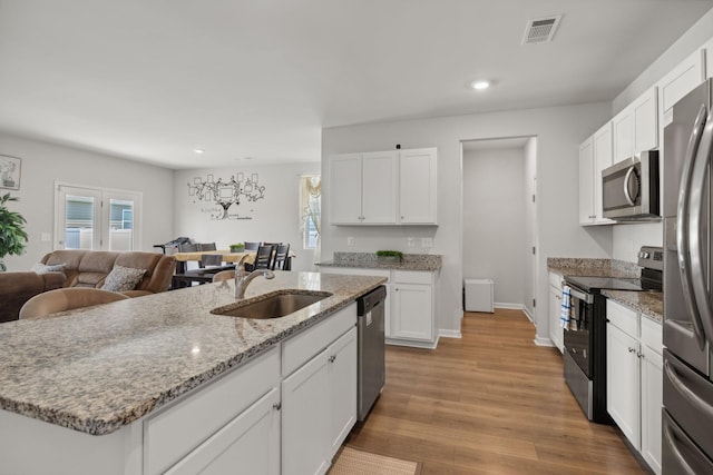 kitchen featuring sink, appliances with stainless steel finishes, a kitchen island with sink, light hardwood / wood-style floors, and white cabinets