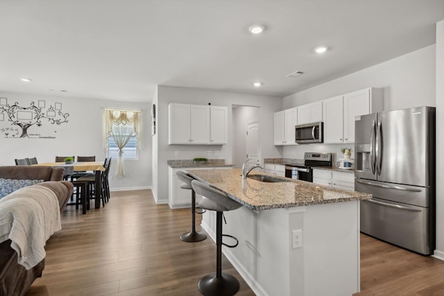 kitchen featuring white cabinetry, stainless steel appliances, sink, and a kitchen island with sink