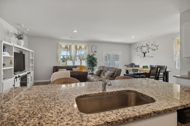 kitchen with stone counters, sink, and hardwood / wood-style floors