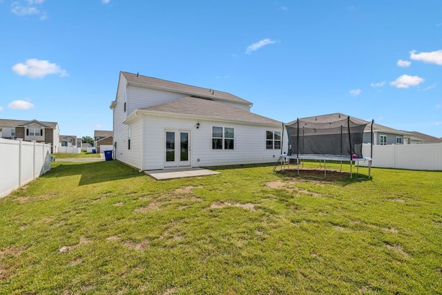 back of house featuring a yard, a trampoline, and french doors